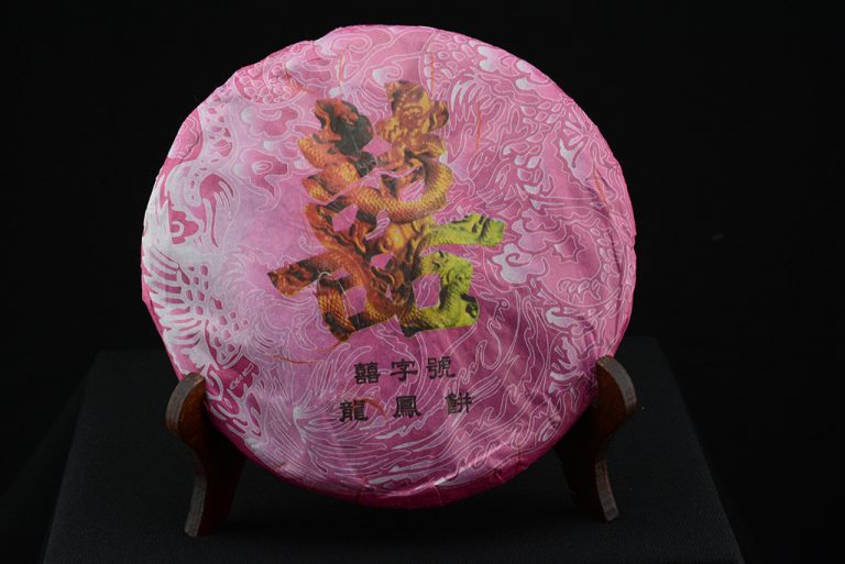 Xi Zhi Hao legendás név a puerh szerető közönség körében. A puerht először Tajvan, Hong-Kong és Japán fedezte fel a nagyvilágnak. Még a nyolcvanas évek végén is csak annyit írt a nyugati populáris és szaksajtó, hogy léteznek ún. öreg, vagy utólag fermentált teák. Amerika még csak kóstolgatta, amikor Tajvanon már lelkes gyűjtőtábora alakult ki a legjobb puerheknek. Egy ilyen gyűjtő, Cheng Úr alapította a kilencvenes évek végén puerh gyártó cégét és annak egy márkáját a Xi Zhi Haot (a dupla szerencse jele). Tajvani, kifinomult, arisztokratikus, nem utolsósorban nosztalgikus igénnyel keresett fel és adott ki minden évben őseredeti, igazi teákat. Esélyünk sem lenne arra, hogy Xi Zhi Hao teákat kóstolgassunk, ha nem lenne a Mengyan Guoyan Teaüzem és annak vezetője Dong Guoyan asszony, aki ebben az évben bérmunkában a Xi Zhi Hao teák gyártását vezényelte, illetve a csomagolást végezte. Így "a szállítószalag mellől" került két kisebb tétel a nyugati teaivók asztalára. Itthon talán soknak tűnik az ára, de el kell mondanom, hogy a tajvani ára ennek a duplájánál is több. Erős, nagyon erős, kitűnően érlelhető fiatal Menghai aroma kísér gyümölcsös, intenzív virágos, finom ízeket. Ügyesen kell elkészíteni, megengedett az árnyalatnyival enyhébb, langyosabb víz használata. 2021 A Xi Zi Hao teák ára az egekben van, a fiatal prémium shengek korongonként ezerháromszáz dollár fölött kaphatók meg. Belépő a sheng puerh teák világába itt és információ az elkészítéséhez itt >>>>>> Még több történetet, információt és teatesztet talál a puerh teák oldalán. Az érlelt sheng és shu puerh teákat egy rövid elmosás után öntjük fel 100 Co fokon ízlés szerint szabályozva a felöntés idejének hosszát. Végig nagyon forró vizet használunk hozzá és a kannát kívülről is folyamatosan fürdetjük. Tartsa napfénytől és idegen illatoktól elzárt hűvös helyen. Megfelelő tárolás mellett minőségét évtizedekig megőrzi. Eszközöket a tea elkészítéséhez tea kellékek kínálatunkból választhat. 2007 Xi Zhi Hao - Sárkány és Főnix - prémium sheng puerh tea
