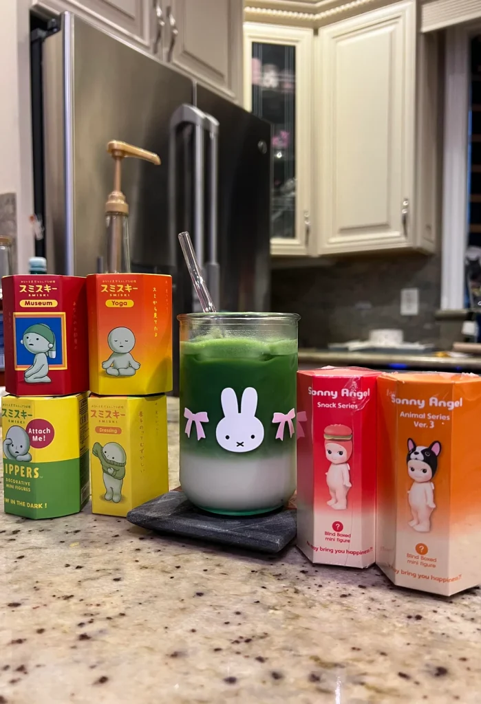 Lapzárta után
Lapzárta után érkezett a hír, hogy a Sonny Angel subreditben is aktív jcch felhasználó felveszi, amint ezekben az ínséges időkben a konyhapulton lazán kinyit egy doboz Matcha Tenjut, majd kedvenc Angeles üvegpoharában latté készít belőle és írói munkássága részeként közzéteszi a világhálón. Az adok kapok szekcióban megvédte választását, nem használta a Wa Kei Sei Jaku szavakat, de elmondta, hogy az olcsóbb matchák neki túl keserűek és csak több agave szirupot kell tennie hozzá, ez viszont kevesebbel is remek. Oldalunk a Matcha Tenju bemutatójaként és a szabad véleménynyilvánítás elkötelezett fórumaként ünnepli a választást és csak az iránt érdeklődünk aggódva, hogy nem lett volna-e jobb a kókuszvirág cukorból és gleccservízből készített szirup?